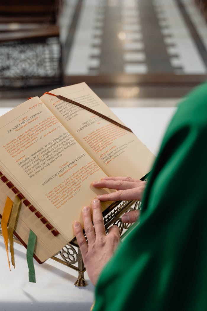 A priest reads from an open Bible in a church setting, symbolizing faith and spirituality.